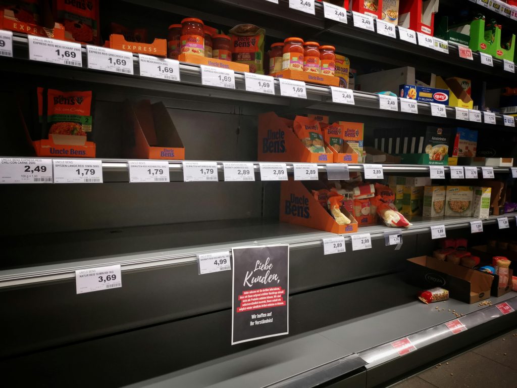 Half empty shelves with assorted products in jars and containers in supermarket during quarantine