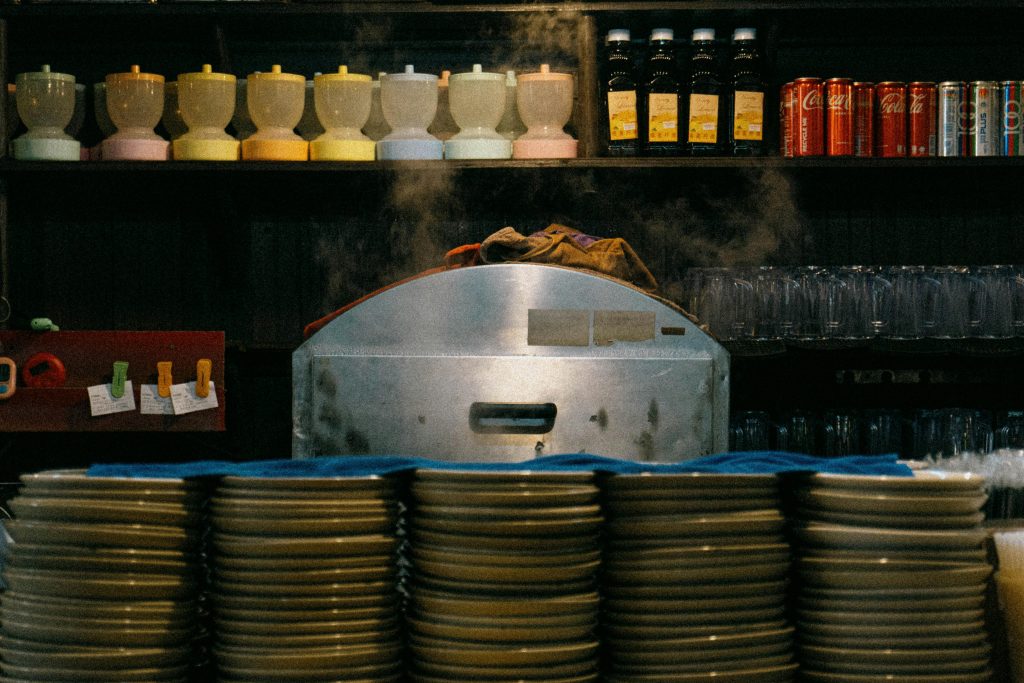 A vibrant kitchen scene with steaming equipment and stacked plates, ideal for culinary themes.