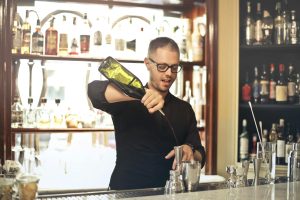 A skilled bartender preparing drinks in a stylish, modern bar setting.