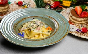 A beautifully presented pasta dish accompanied by a fresh tiramisu on a restaurant table.