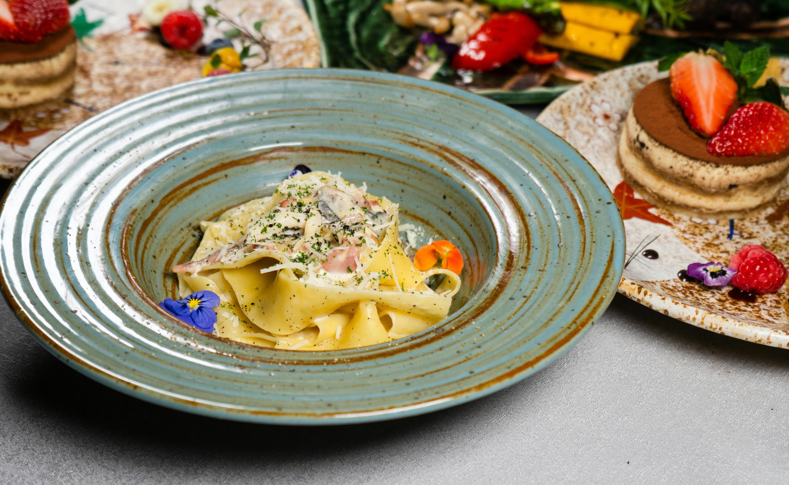 A beautifully presented pasta dish accompanied by a fresh tiramisu on a restaurant table.