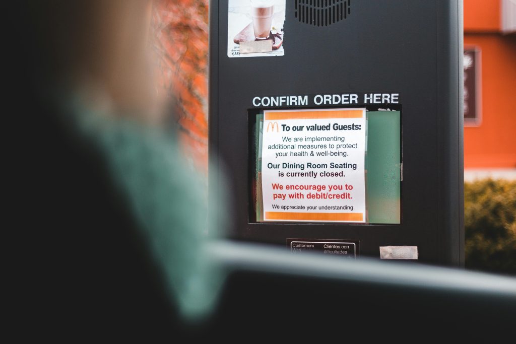 A drive-thru ordering sign with health advisory notice at a fast food restaurant.