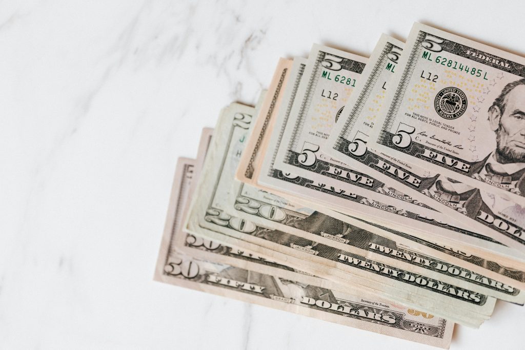 Close-up shot of various US dollar bills on a marble tabletop, showcasing finance and wealth.