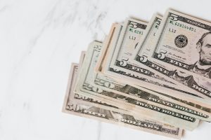 Close-up shot of various US dollar bills on a marble tabletop, showcasing finance and wealth.