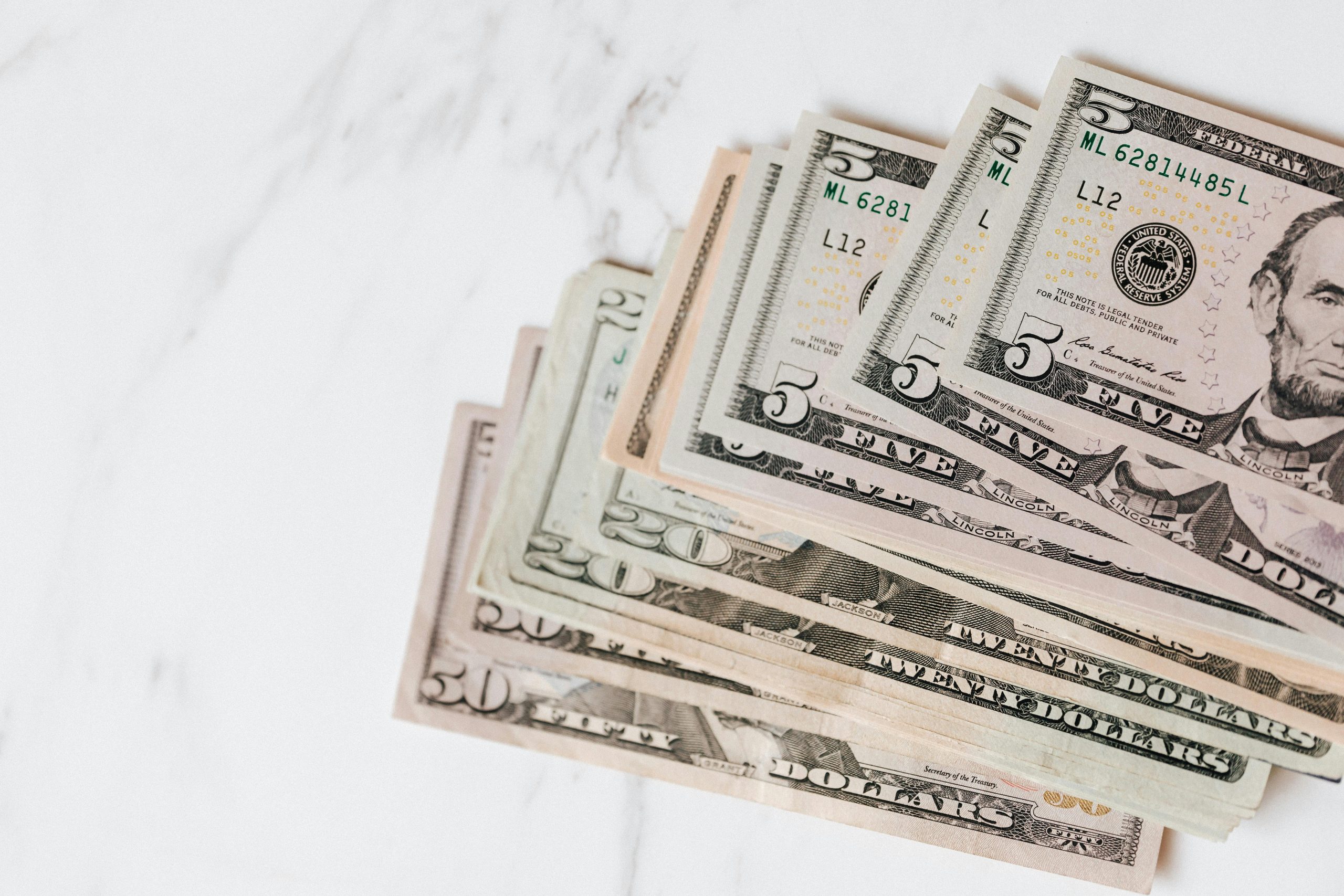 Close-up shot of various US dollar bills on a marble tabletop, showcasing finance and wealth.